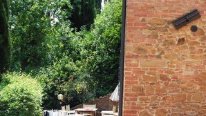 Eine Terrasse mit Backsteinmauer, Gartenmöbeln und üppiger Bepflanzung.