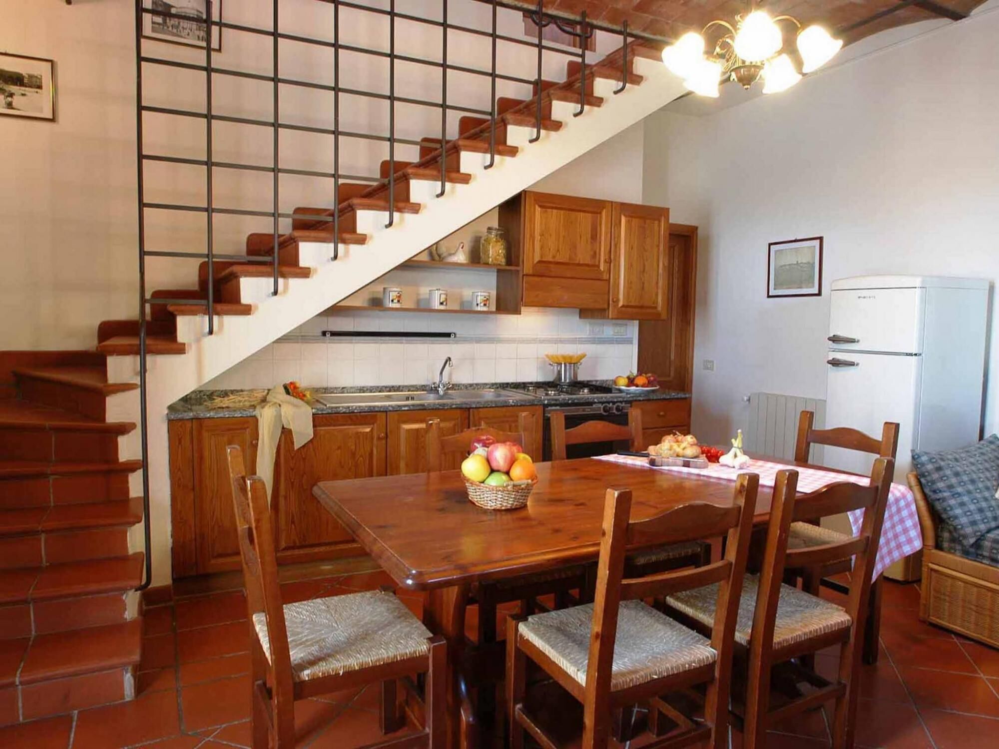 Uma cozinha com armários de madeira, uma mesa de jantar com cadeiras e uma escada.