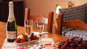 Une table à manger avec une bouteille de champagne La Vallée, deux verres de champagne, une assiette de fraises, un bol de crème glacée et une assiette de raisins.
