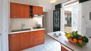 A modern kitchen with wooden cabinets, a gas stove, and a white countertop. - Relais San Basilio Convento - ID 3061 (Amalfi)