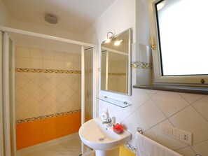 A bathroom with a shower, a sink, a mirror, and a towel rack.