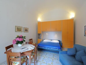 Une chambre à coucher comprenant un lit, un canapé, une table à manger avec des chaises et un vase de fleurs.