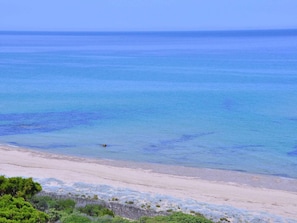 A beach with clear blue water and a sandy shore.