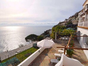 Una terrazza con vista sul mare, arredi esterni e un pergolato con piante.