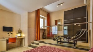 Une chambre d’hôtel équipée d’un lit, d’un bureau, d’une chaise, d’une télévision et d’un balcon avec vue.