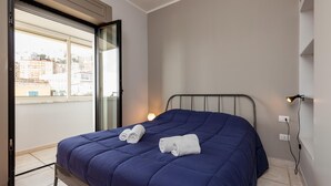 Un dormitorio con cama, ventana y toma de corriente.