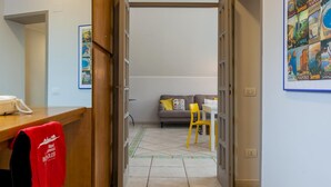 Un pasillo que conduce a una sala de estar con un sofá, un sillón amarillo y una mesa.