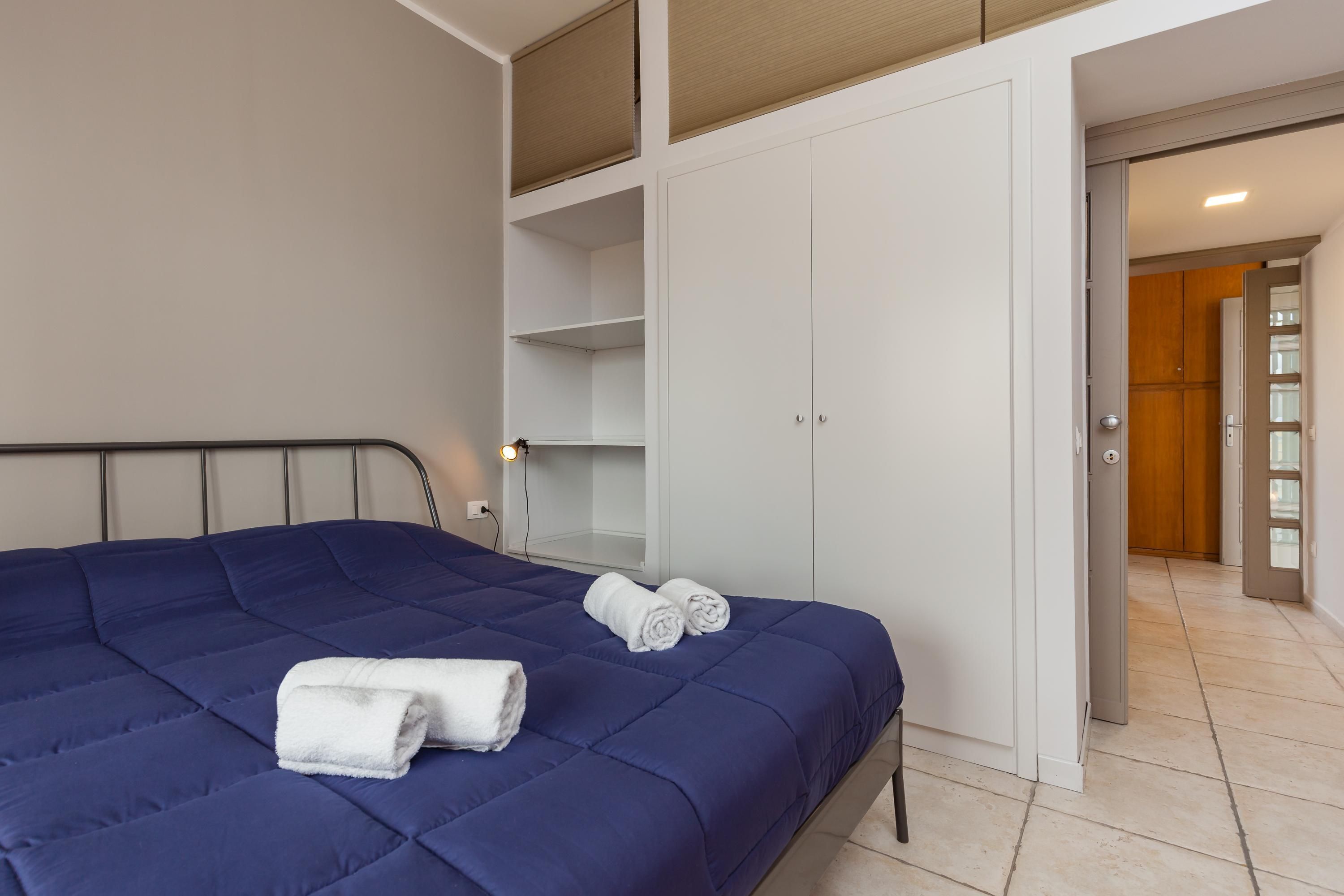 A bedroom with a bed, a wardrobe, and a bathroom door.
