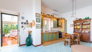 A spacious living area with a dining table, a sofa, and a kitchen with wooden cabinets and a built-in oven. - Terrazza Morgera in Napoli (Casamicciola Terme)