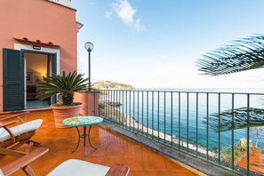 A balcony with a view of the sea, a table, chairs, and a potted plant. - Terrazza Morgera in Napoli (Casamicciola Terme)