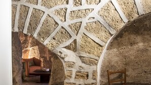 Une pièce aux murs de pierre, avec une chaise en bois et un canapé.