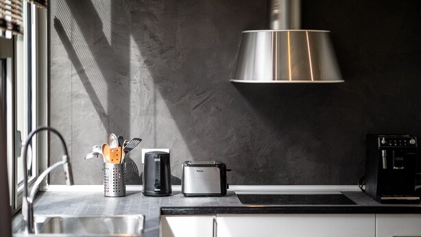 A modern kitchen with a stainless steel toaster, a coffee machine, and a kettle on the counter. - Le Loft Horloger (Besançon)