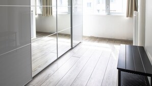 A modern room with a sliding glass door, a black bench, and a view of buildings outside. - Le Loft Horloger (Besançon)