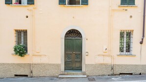 A building with a central arched door, two windows with shutters, and a small plant on the left. - Co-c520-vmon4a1 - Amazing Cernobbio (Cernobbio)