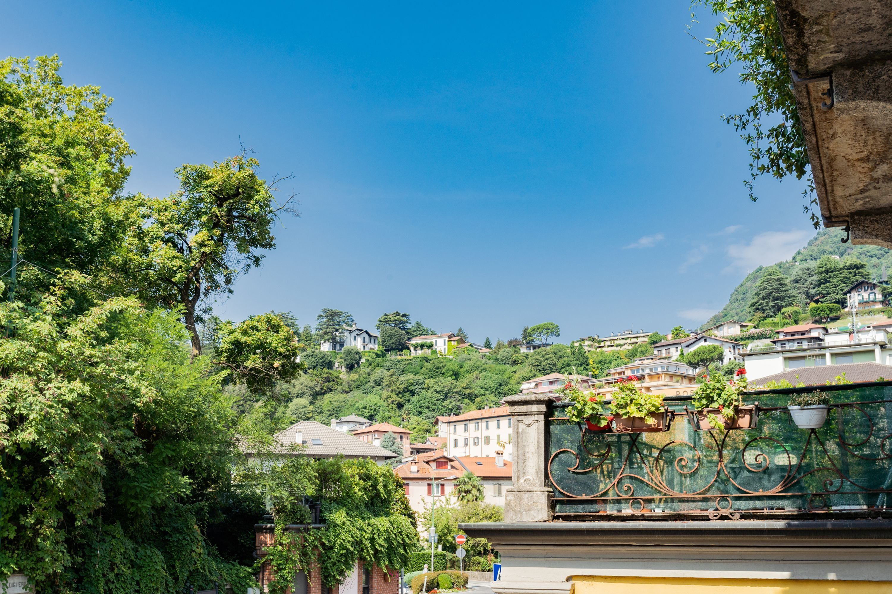 Un barrio residencial con casas en una ladera, cielo azul despejado y vegetación.