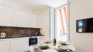 A modern kitchen with white cabinets, a gas stove, and a dining area with a table set for two. - Co-c520-vmon4a1 - Amazing Cernobbio (Cernobbio)