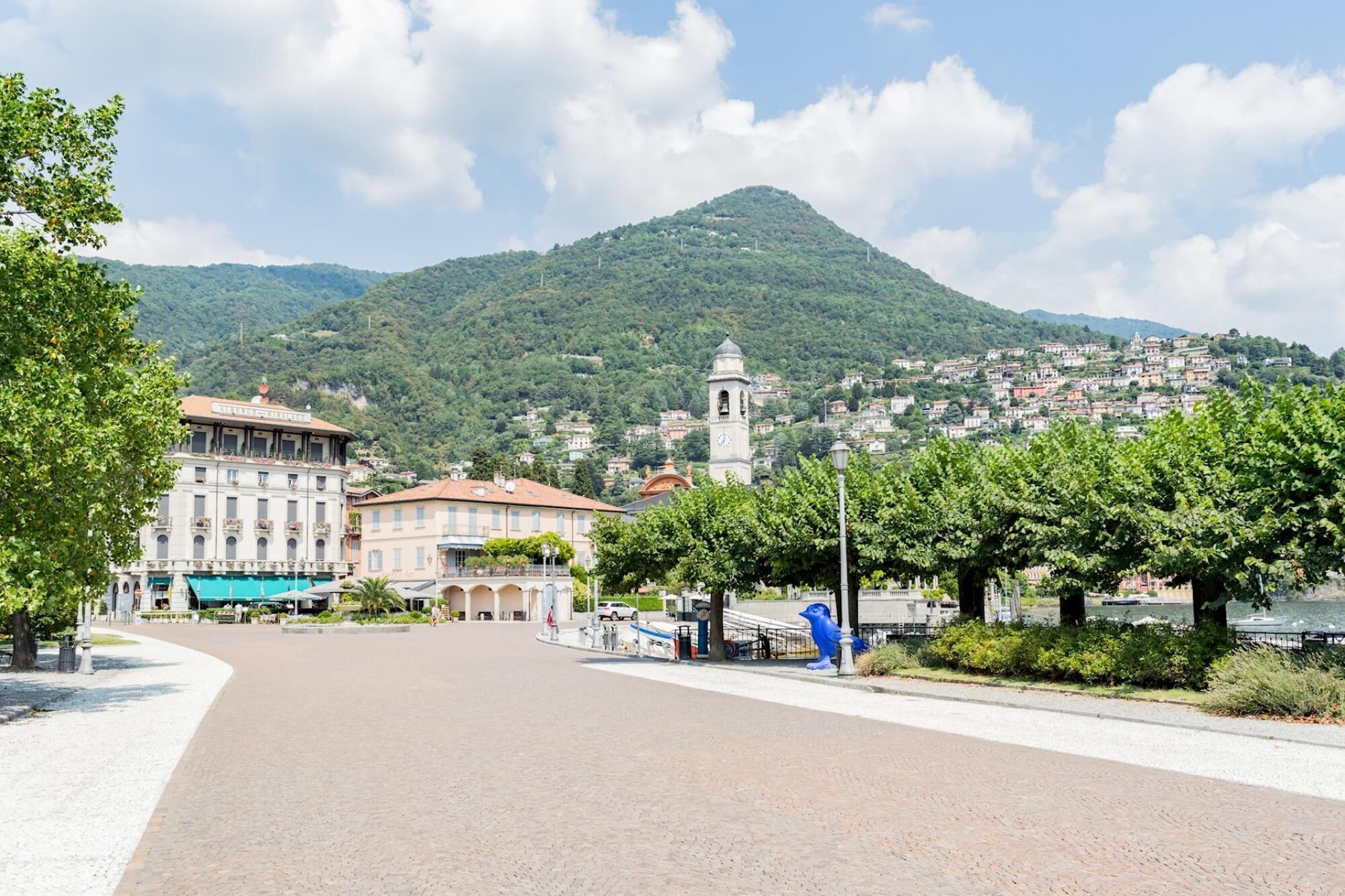 A town square with buildings, a clock tower, and a mountain in the background.