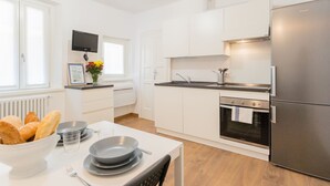 A modern kitchen with white cabinets, a stainless steel refrigerator, and a dining area with a table set for two. - Da Pia in Historycal Como City Centre (Como)