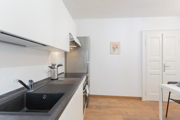 Una cucina moderna con lavello nero, mobili bianchi e pavimento in legno.