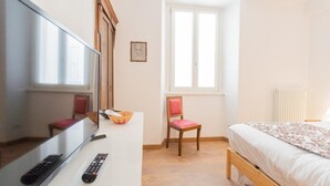 A bedroom with a bed, a chair, a TV, and a window. - Da Pia in Historycal Como City Centre (Como)