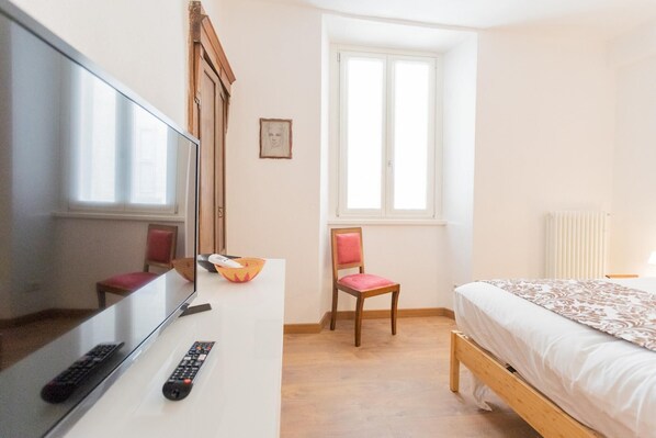 A bedroom with a bed, a chair, a TV, and a window. - Da Pia in Historycal Como City Centre (Como)