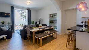 Ein modernes Wohnzimmer mit einer Couch, einem Esstisch und einer Küchenzeile mit Barhocker.