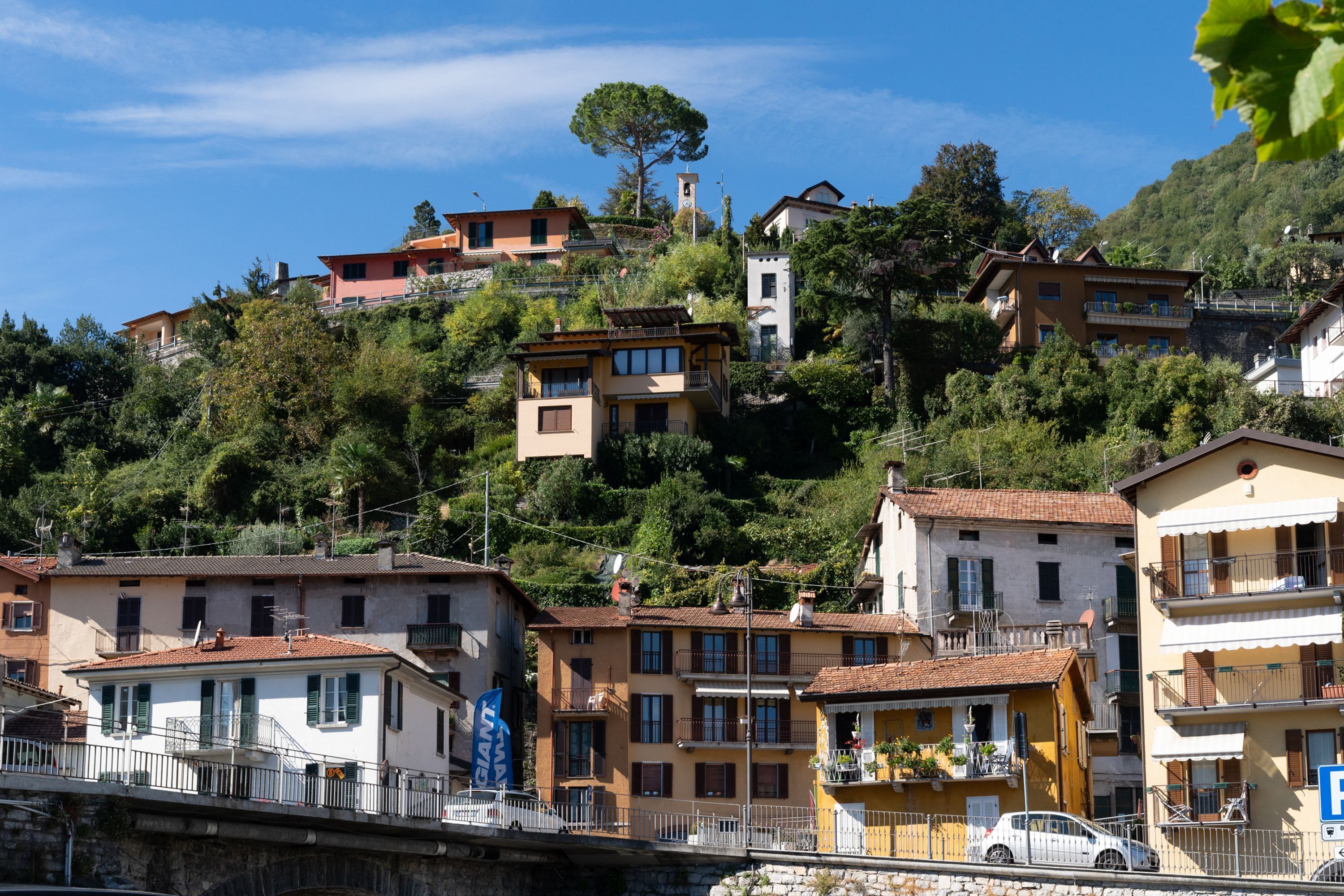 Una zona residencial en una ladera con edificios de varios pisos, balcones y un cielo azul despejado.