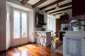 Une cuisine avec des poutres en bois, un coin repas avec des chaises et une vue par la fenêtre.