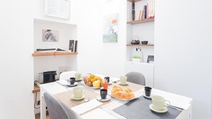 A modern, well-lit room with a dining table set for breakfast, bookshelves, and artwork on the walls. - Co-c933-dott13a2 - Rosart House (Como)