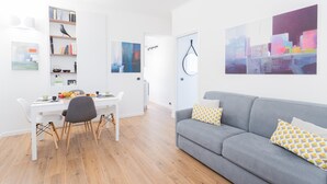 A modern living room with a grey sofa, a dining table with chairs, and a bookshelf. - Co-c933-dott13a2 - Rosart House (Como)