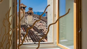 A view through a window with a clear sky, a tiled roof, and a building with a traditional architectural style. - Co-m341-sabb12a1 - Sunny Corner Near Bellagio (Tremezzina)