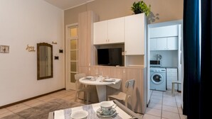 Ett kompakt bostadsutrymme med en matplats, ett litet kök och en tvättstuga.