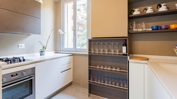 A modern kitchen with white cabinets, a built-in oven, and a wine rack.