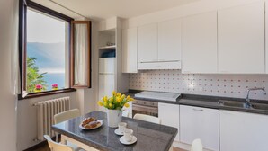 Eine moderne Küche mit weißen Schränken, einer Granitarbeitsplatte und Meerblick durch ein Fenster.