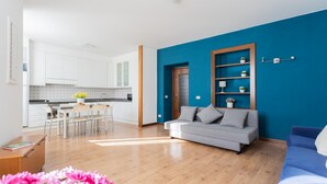 Ein modernes Wohnzimmer mit blauer Akzentwand, einem grauen Sofa und Holzboden.