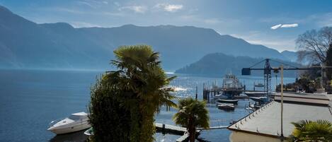 A marina with boats docked, a clear sky, and mountains in the background.