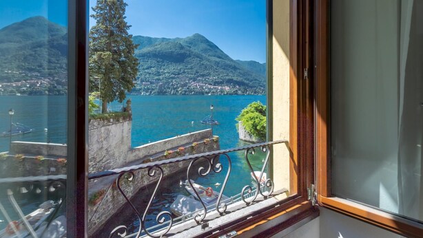 Ein Balkon mit Blick auf einen See, Berge und eine Stadt im Hintergrund.