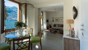 Ein modernes Wohnzimmer mit einem Glastisch, Holzstühlen, einer Couch und Meerblick.