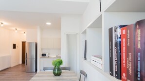 A modern kitchen with a built-in microwave, a stainless steel refrigerator, and a dining area with a wooden table and chairs. - Co-c933-ggar24c4 - Central Green Apartment (Como)
