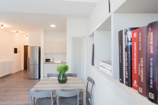 A modern kitchen with a built-in microwave, a stainless steel refrigerator, and a dining area with a wooden table and chairs.