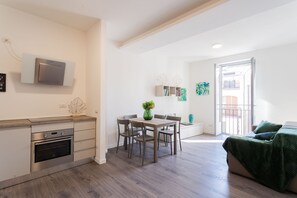 Una cocina moderna con horno y microondas integrados, un comedor con mesa y sillas, y un balcón con vistas.