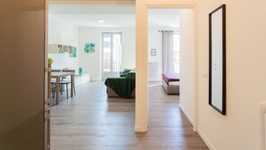 A spacious living area with a dining table and chairs, a sofa, and a green blanket on the floor. - Co-c933-ggar24c4 - Central Green Apartment (Como)