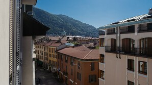 A view of a building with a balcony overlooking a street and a hill with a church.