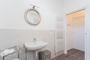 Une salle de bain avec un lavabo blanc, un miroir et un porte-serviettes.