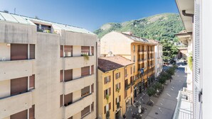 A street view with buildings, a clear sky, and a hilly landscape in the background. - Co-c933-ggar24c4 - Central Green Apartment (Como)