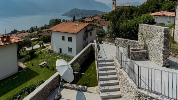 Un quartier résidentiel avec un escalier en pierre menant à un bâtiment blanc surmonté d’un toit recouvert de tuiles rouges.