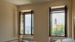 Une chambre à coucher avec un lit, deux fenêtres et une vue sur une tour.