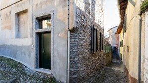 Eine schmale Kopfsteinpflasterstraße, gesäumt von historischen Steinbauten mit einer grünen Tür und einem Fenster.