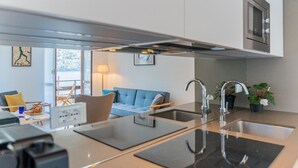 A modern kitchen with a central island, stainless steel appliances, and a view to a living area with a sofa and a table. - Co-e405-regi74a1 - Your Private Harbour Nearby George Clooney (Carate Urio)