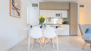 A modern kitchen with white cabinets, a microwave, and a dining area with two white chairs and a table. - Co-e405-regi74a1 - Your Private Harbour Nearby George Clooney (Carate Urio)